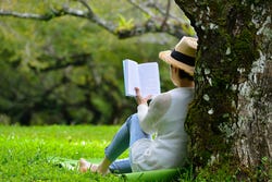 Vrouw leest een boek in de koele schaduw van een boom Vrouw leest een boek in de koele schaduw van een boom