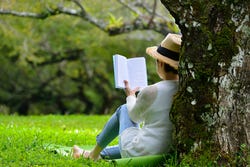 Vrouw leest een boek in de koele schaduw van een boom