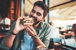 Man neemt een grote hap van een smakelijke sandwich Man neemt een grote hap van een smakelijke sandwich