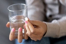 Twee handen met een pil en een glas water Twee handen met een pil en een glas water