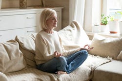 Een vrouw leert te mediteren op haar bank Een vrouw leert te mediteren op haar bank