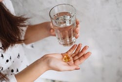 Vrouw met handvol supplementen en glas water Vrouw met handvol supplementen en glas water