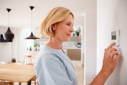 Vrouw zit aan de thermostaat Vrouw zit aan de thermostaat