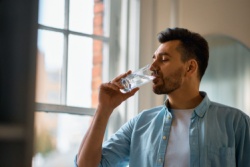 Man drinkt water uit een glas