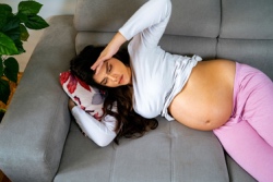 Vermoeide zwangere vrouw ligt op de bank