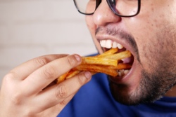 Man neemt een grote hap frietjes