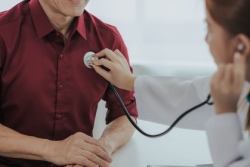 Vrouwelijke arts luistert met stethoscoop naar het hart van een man