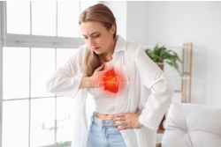 Jonge vrouw grijpt voorovergebogen naar haar hart