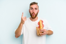 Jonge man eet een broodje salami