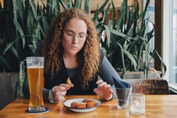 Vrouw met glas bier eet bitterballen