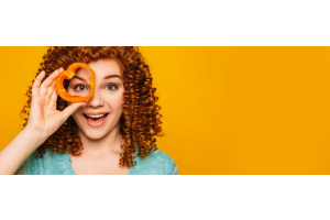 Vrouw houdt een stuk paprika voor haar oog