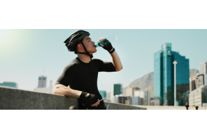 Man met fietshelm op drinkt uit een fles water