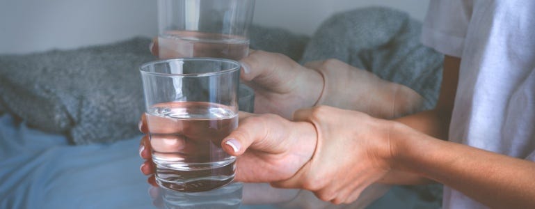 Bevende handen met glas water