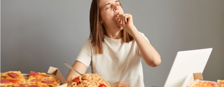 Vrouw is vermoeid na het eten van allerlei ongezonde snacks
