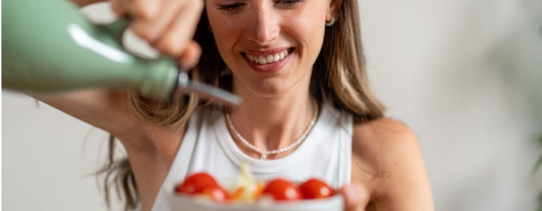 Vrouw schenkt extra vergine olijfolie over haar gezonde salade