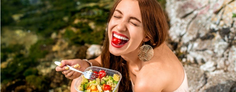 Blije vrouw smult van salade