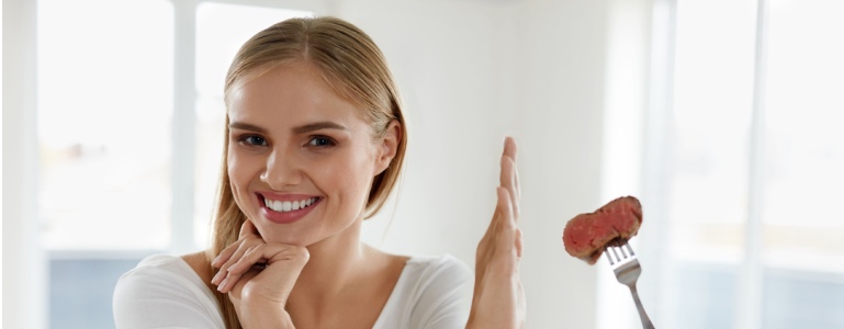 Vrouw wijst met haar hand een stuk vlees af