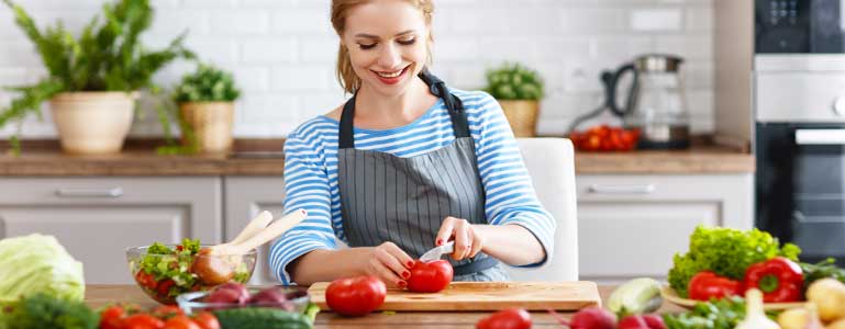 Vrouw in de keuken die groente snijdt