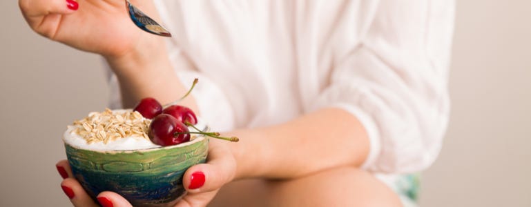 Mevrouw eet schaaltje yoghurt met kersen