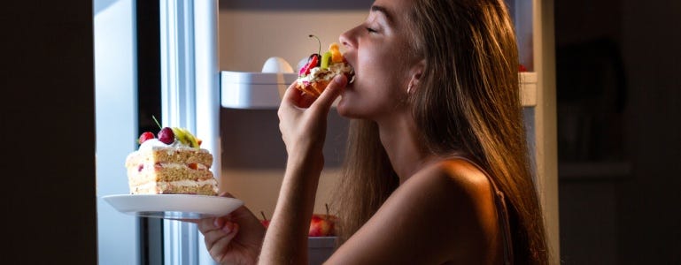 Vrouw eet een stuk taart uit de koelkast
