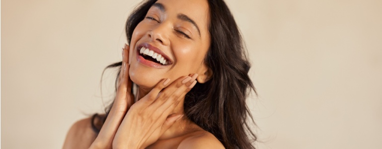 Lachende vrouw raakt met haar handen haar gezicht aan