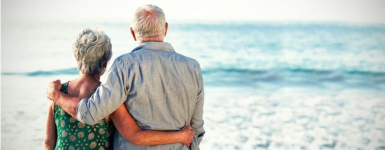 Twee gearmde oudere mensen kijken uit over de zee