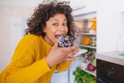 Vrouw neemt hapje van een donut Vrouw neemt hapje van een donut