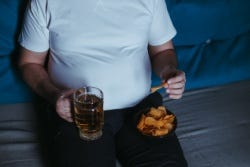 Man zit op de bank met een glas bier en een schaaltje chips Man zit op de bank met een glas bier en een schaaltje chips