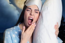 Vrouw gaapt met kussen in haar hand Vrouw gaapt met kussen in haar hand
