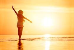 Vrouw bij de ondergaande zon aan het strand Vrouw bij de ondergaande zon aan het strand