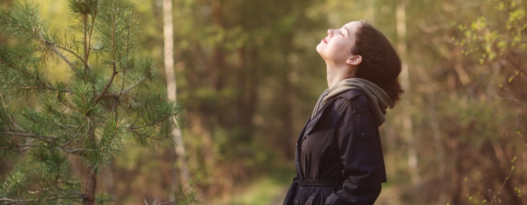 Vrouw ademt frisse boslucht in