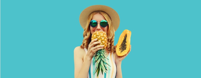 Vrouw houdt ananas en papaja in haar handen