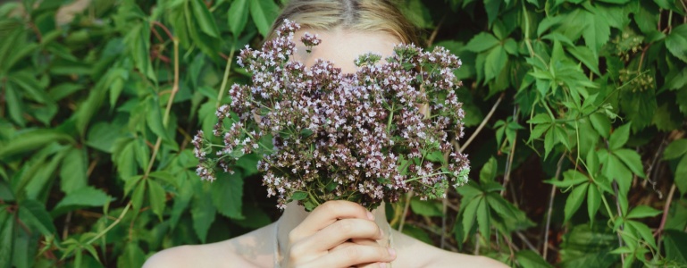 Vrouw met bos oregano voor haar gezicht