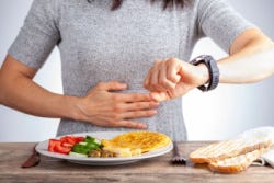 Vrouw die op klok kijkt tot ze weer mag eten Vrouw die op klok kijkt tot ze weer mag eten