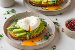 Boterham met plakjes avocado, kiemgroente en een gepocheerd ei Boterham met plakjes avocado, kiemgroente en een gepocheerd ei
