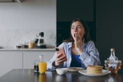 Vrouw gaapt aan de ontbijttafel Vrouw gaapt aan de ontbijttafel