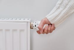 Vrouwenhand draait aan de verwarming Vrouwenhand draait aan de verwarming