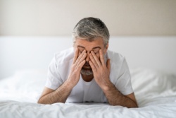 Man ligt in bed en wrijft in zijn ogen
