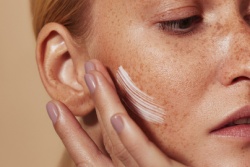 Vrouw smeert cr&egrave;me op haar wang