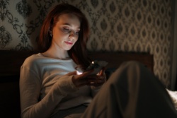 Vrouw scrollt in bed op haar telefoon