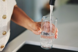 Vrouw schenkt een glas water in