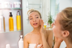 Jonge vrouw doet haar huidverzorging voor de spiegel