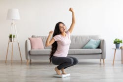 Vrouw op de weegschaal die blij is met gewichtsverlies Vrouw op de weegschaal die blij is met gewichtsverlies
